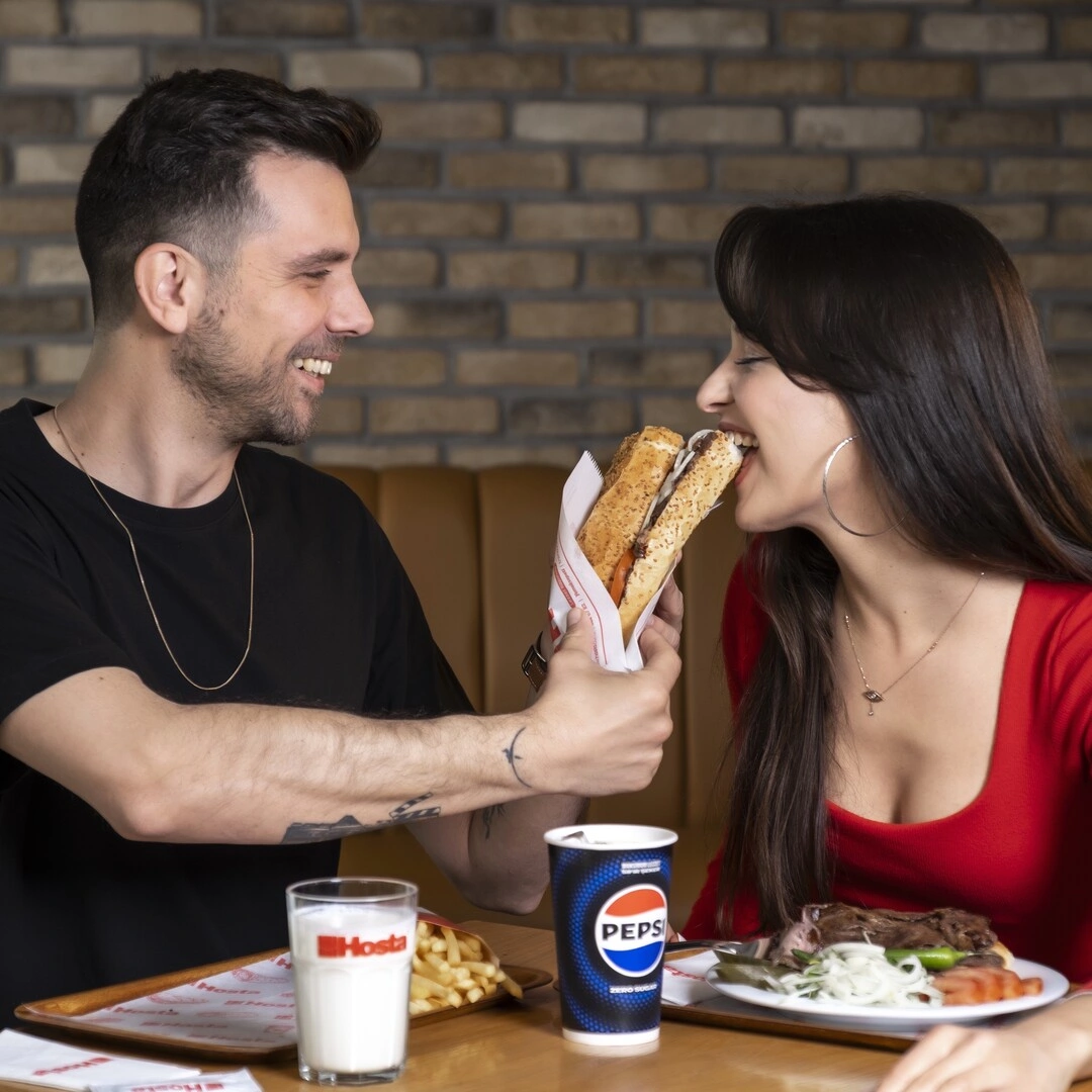 Biri ekmek arası, diğeri tabakta döner yiyen iki kişi Hosta'da yemek yiyor.