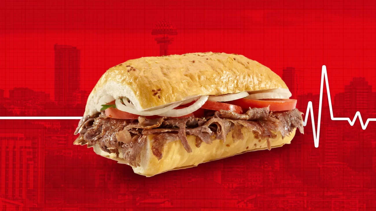 Kırmızı arka plan üzerinde beyaz kalp atışı çizgisi ve arkada Ankara siluetiyle öne çıkarılmış lezzetli et döner görseli.