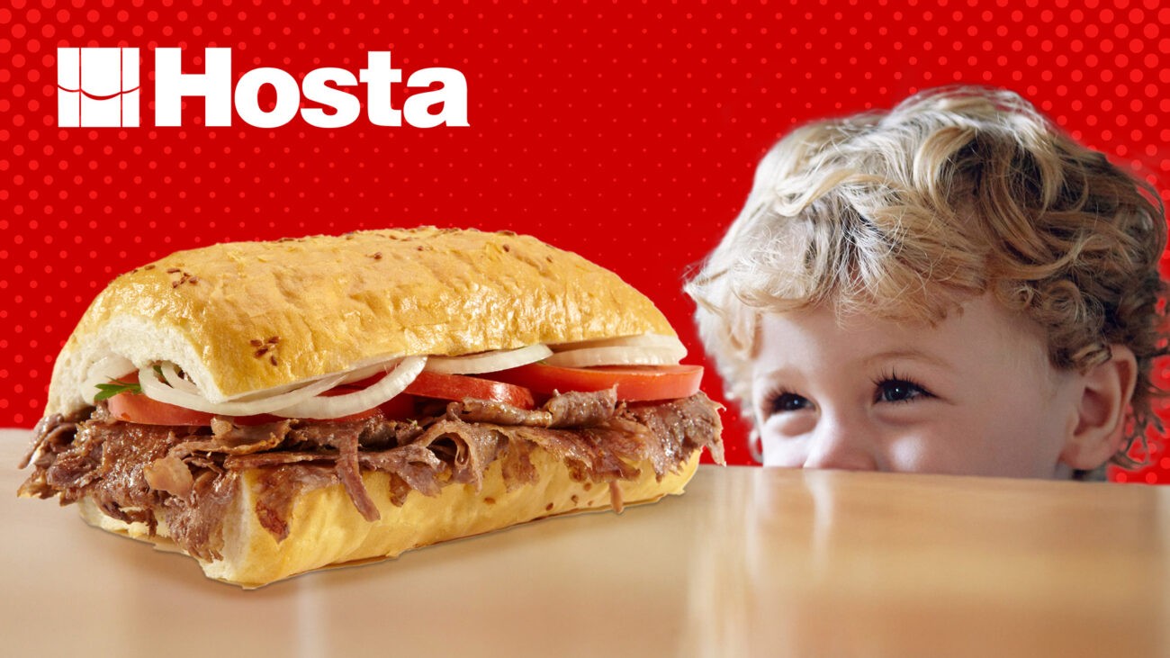 Mutlu bir çocuğun masanın altından masanın üzerindeki ekmek arası Hosta yaprak dönere baktığı görsel.