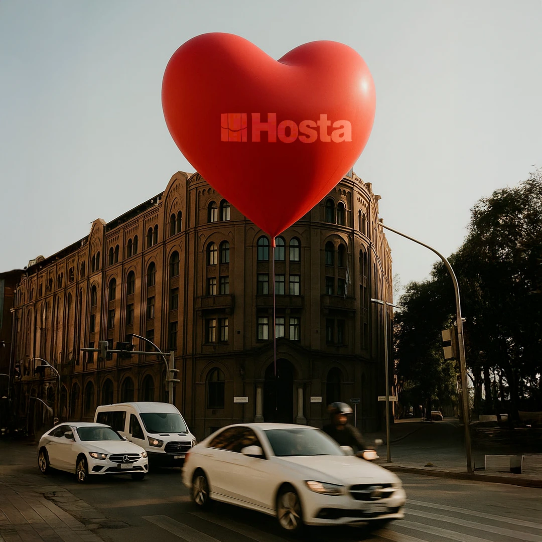Ankara Ulus’ta cadde üzerinden geçen araçlar ve arkadaki tarihi binayı kapatan, üzerinde Hosta logosu bulunan kırmızı balon.