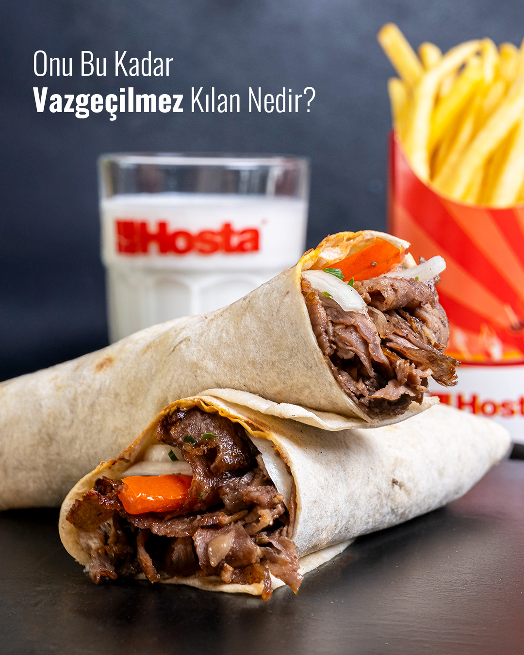 Ön planda dürüm et döner, arka planda Hosta patates ve ayran ile sol üstte “Onu Bu Kadar Vazgeçilmez Kılan Nedir?” yazısı bulunan görsel.